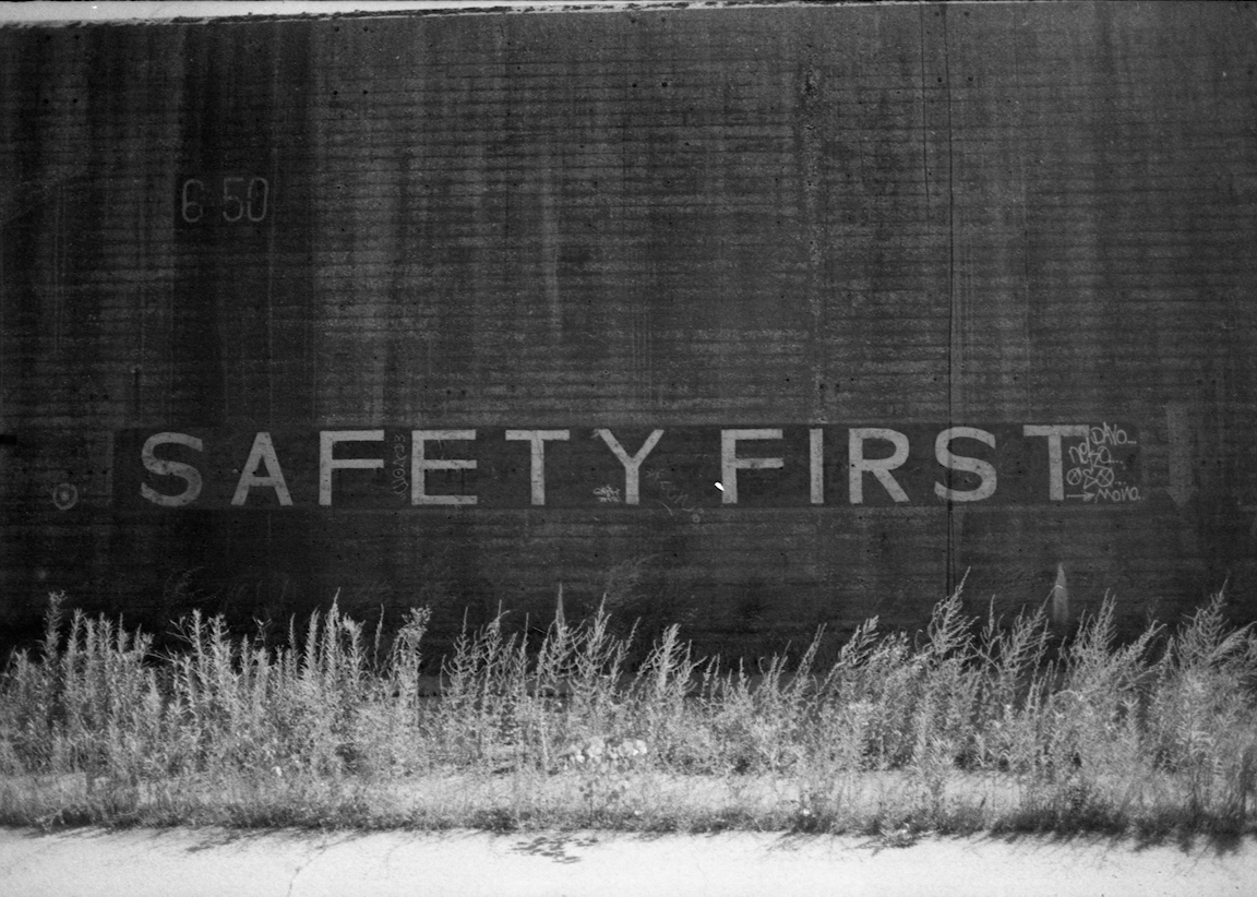 A black-and-white photo of a wall with text that reads "SAFETY FIRST."